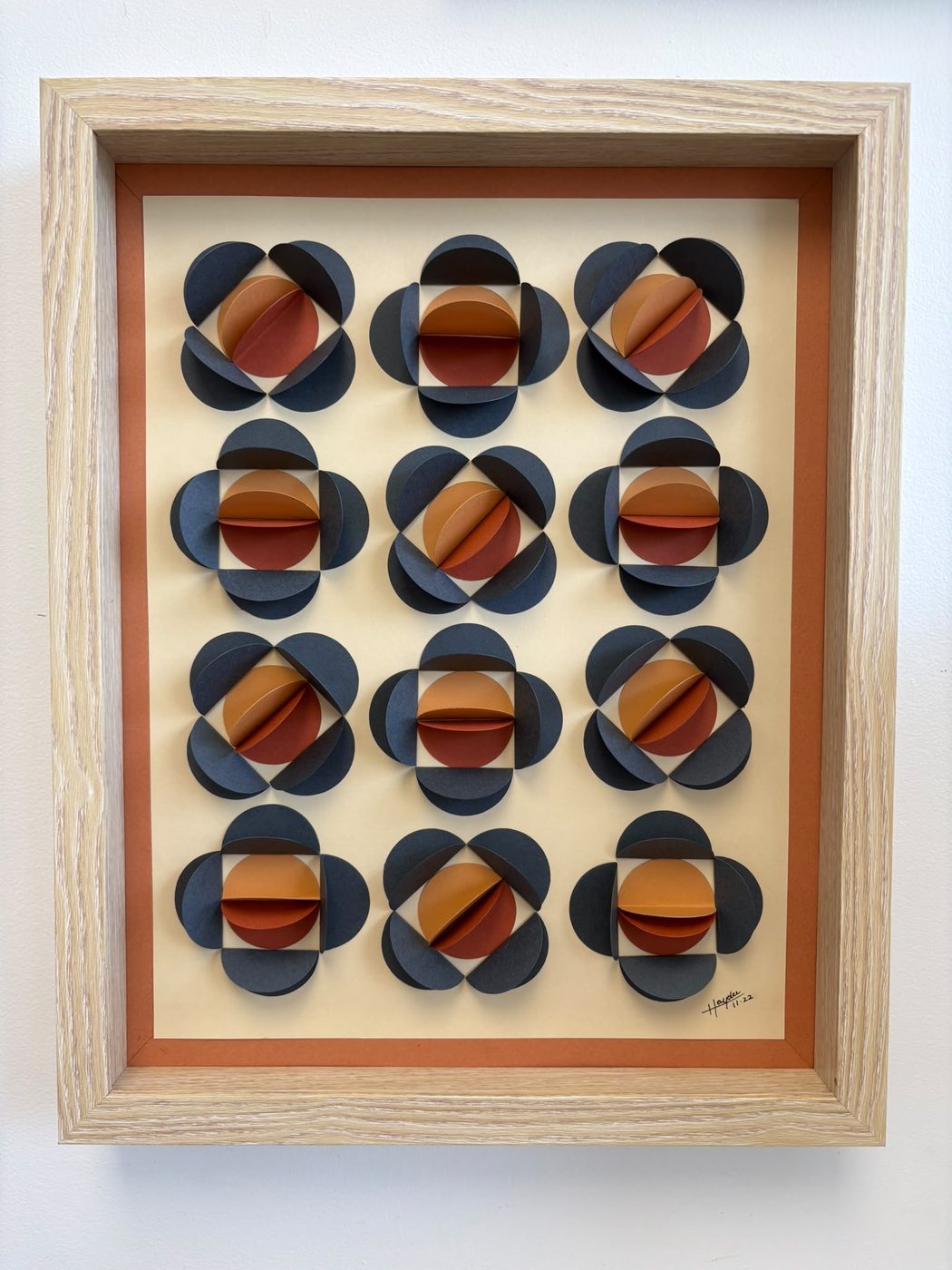 Framed paper wall piece of a navy and rust circle grid
