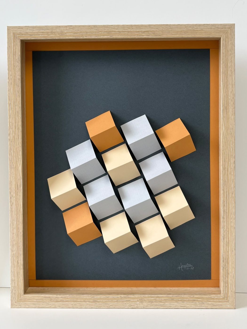 Detail of a framed 3D cube wall piece in orange and grey