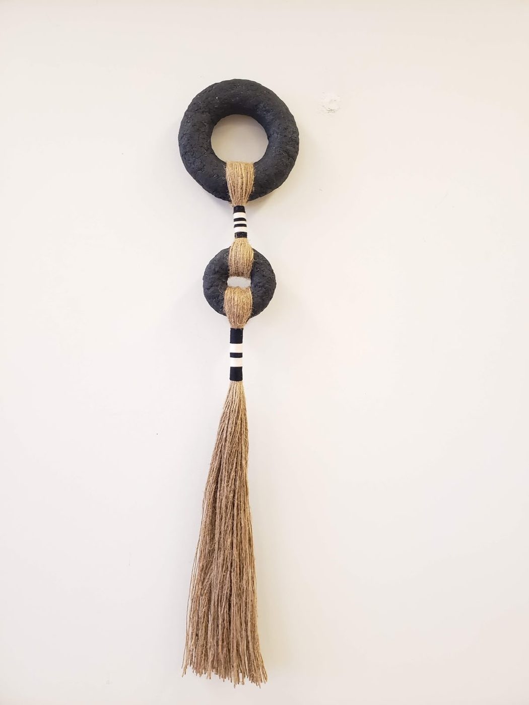 Wall hanging with a black wooden ring and tan tassel