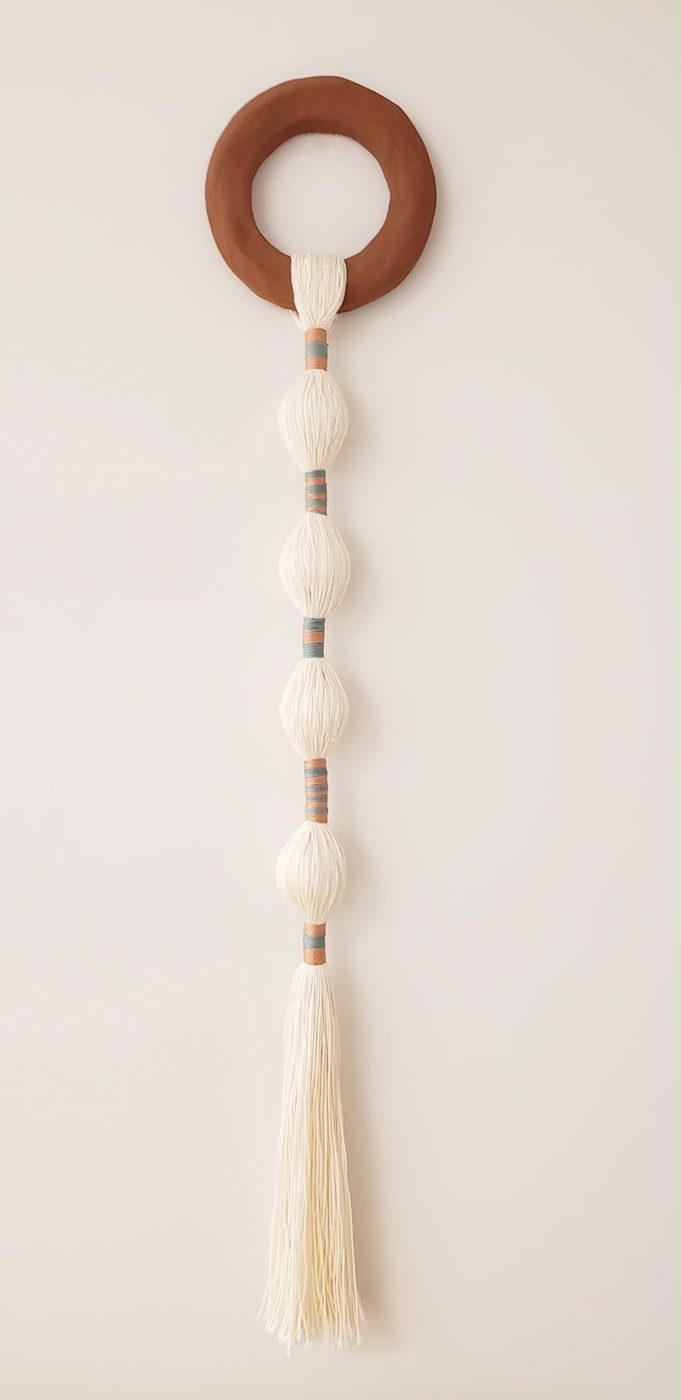Wall hanging with a wooden ring and cream fiber tassel