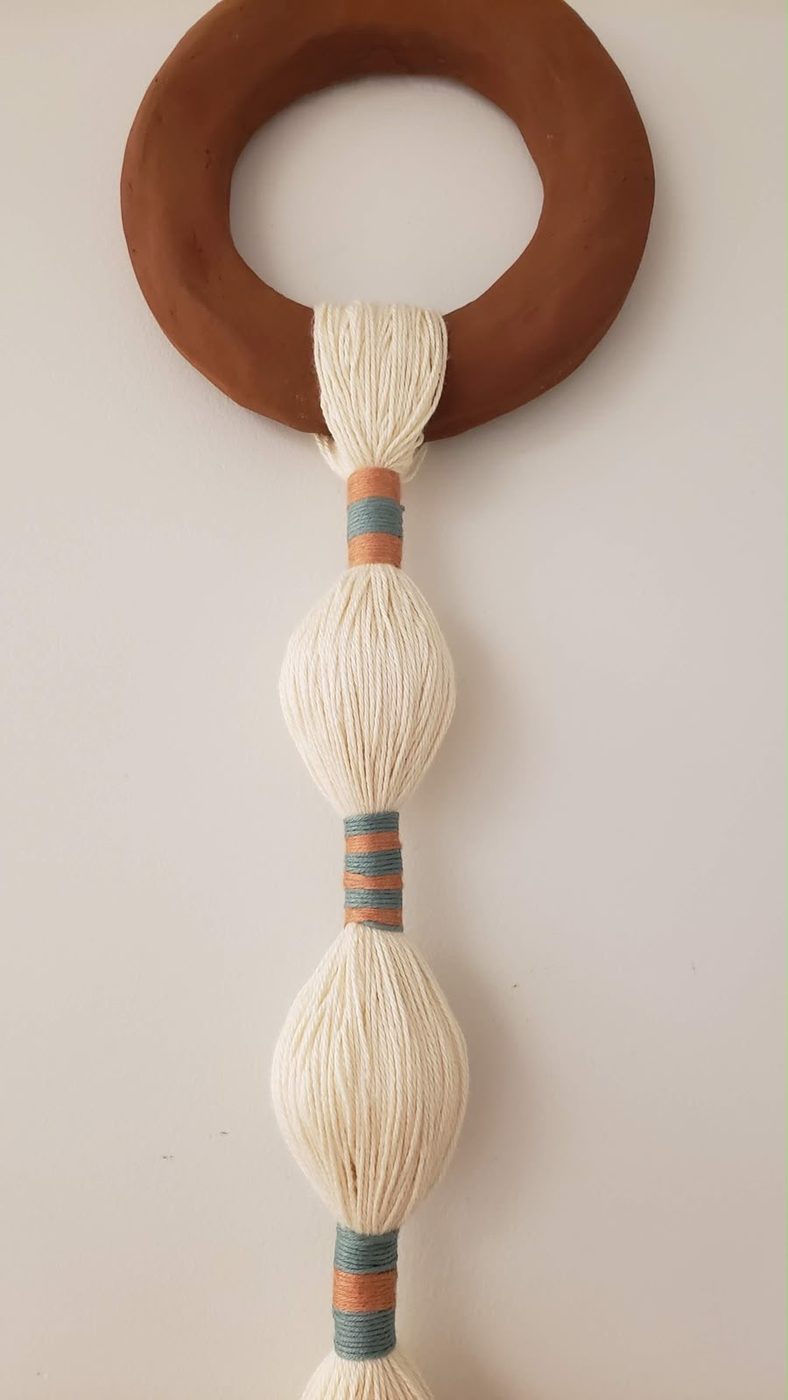 Wall hanging with a wooden ring and cream and rust striped tassel