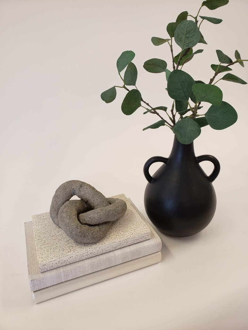 Still life of a vase and a knotted stone on books