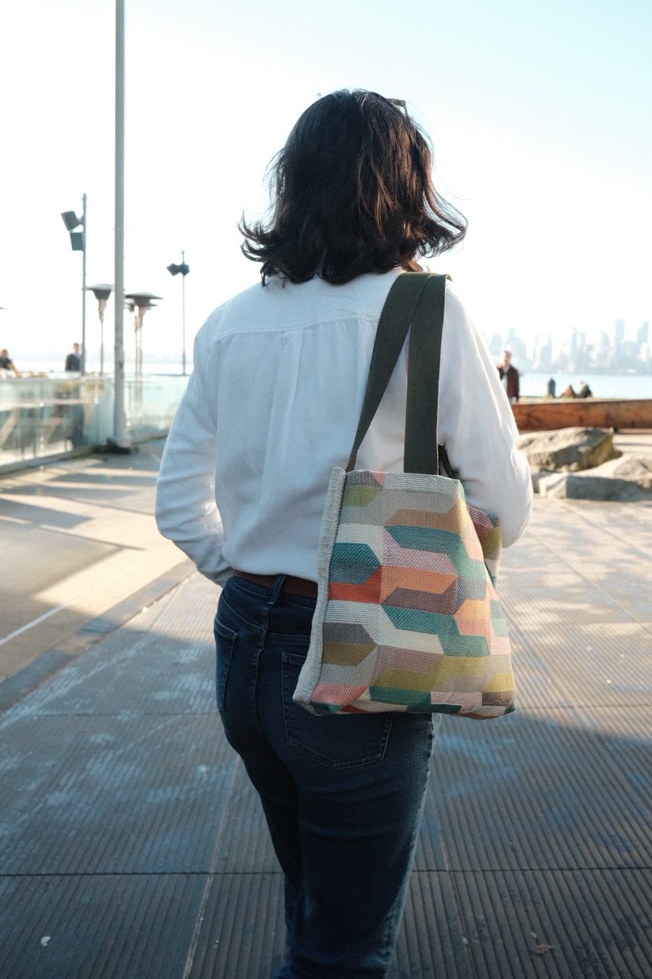 Woman carrying a woven chevron-striped tote on the waterfront